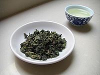 Loose leaf Chinese Fujian: Ti Kuan Yin Oolong tea in a bowl with chinese teacup