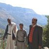 Three men posing on cliff in front of Haimi landscape in Yemen
