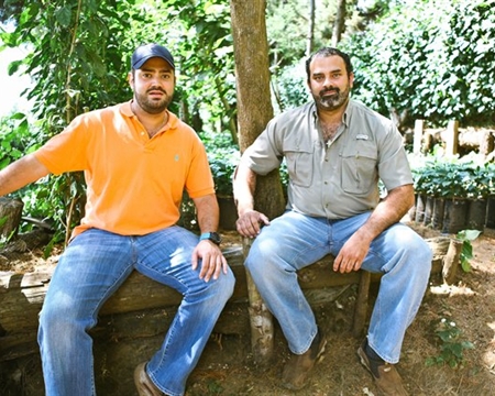 Two men sitting on a log bench outdoors at Cerro Las Ranas