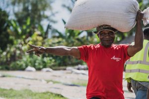 Worker carrying large sack of coffee beans on his head at Kunjin, Papua New Guinea