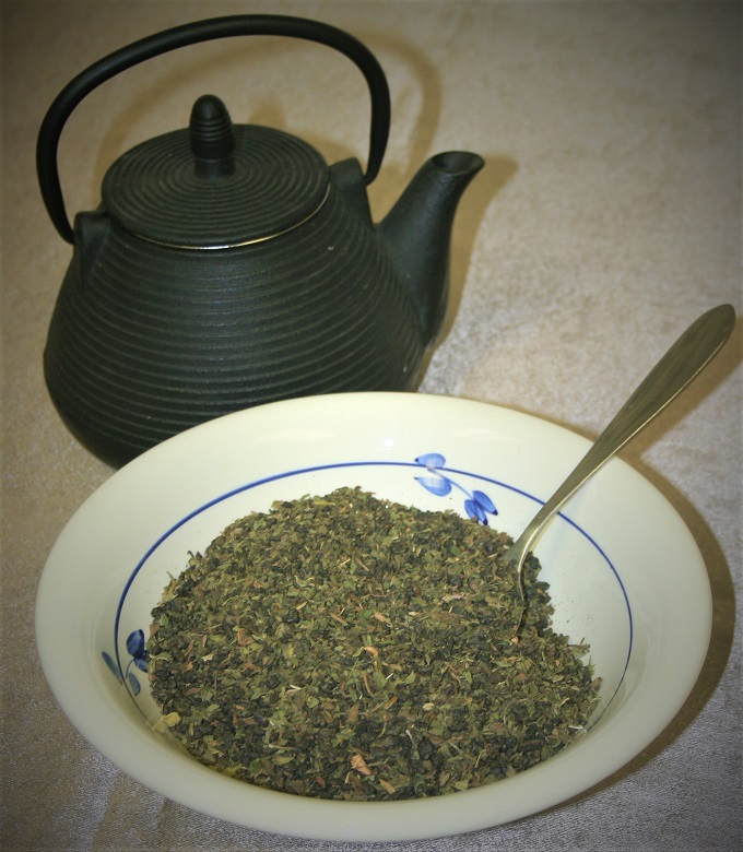 Loose leaf moroccan mint green tea in a bowl with a spoon next to a kettle