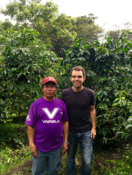 Two people posing in front of coffee trees