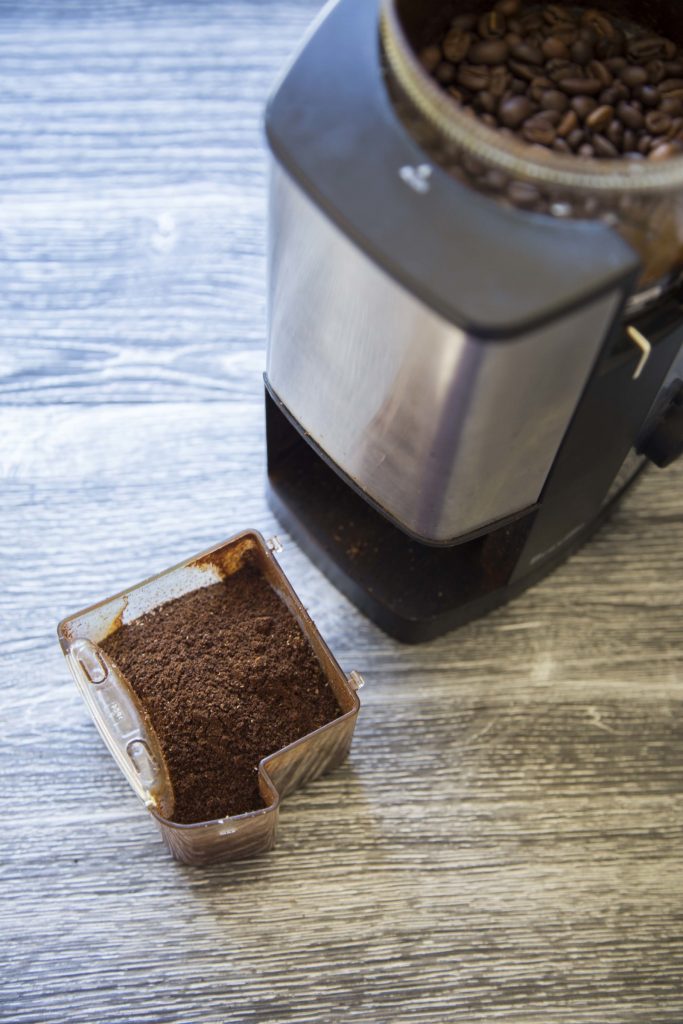 Electric burr coffee grinder needing cleaning.