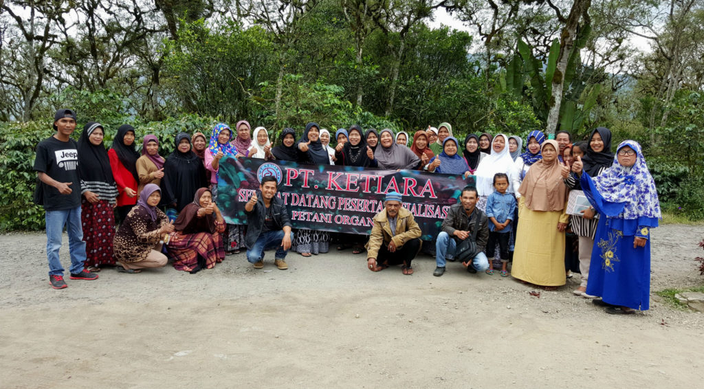Workers at Ketiara posing together outside with a sign