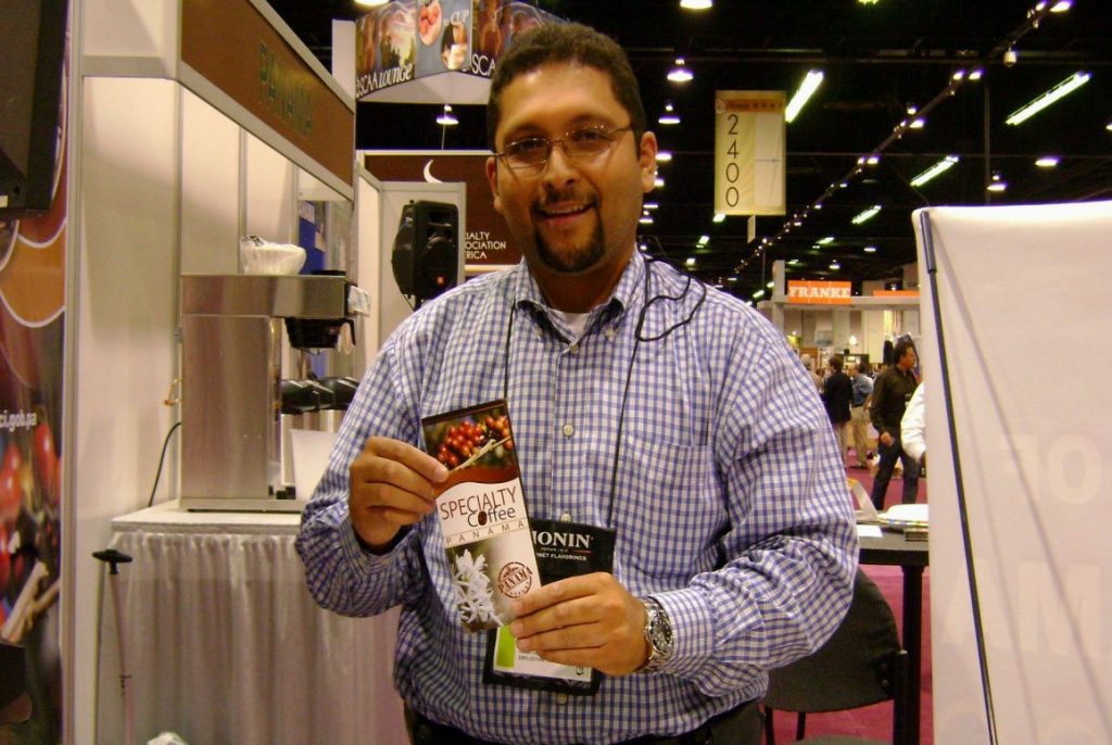 César Araúz standing in a convention hall holding a brochure