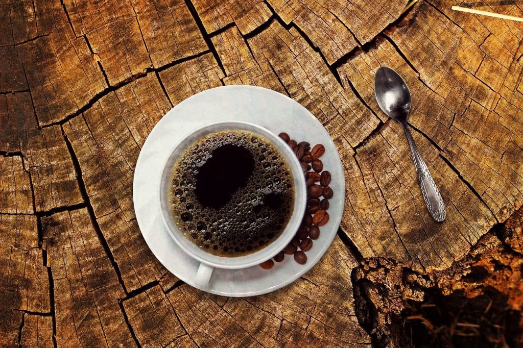 Cup of coffee and spoon on a stump