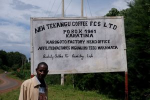 Man standing in front of sign for sign for Tekangu Karagoto in Kenya Nyeri