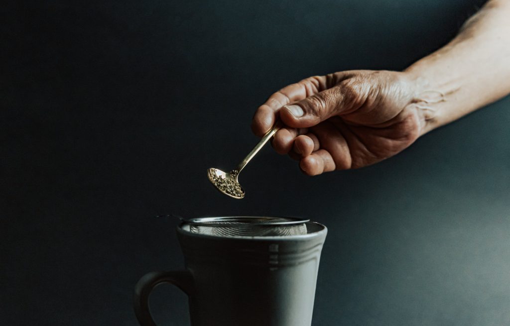 Pouring tea leaves into infuser.